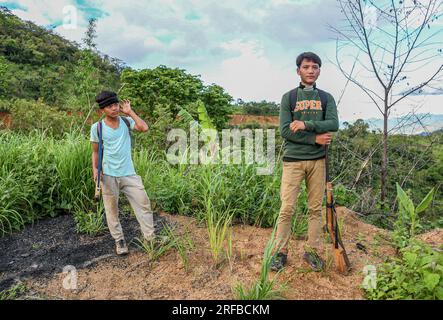 22 giugno 2023, Churachandpur, Manipur, India: I ragazzi Kuki armati reagiscono alla telecamera mentre aspettano i loro amici vicino a un checkpoint nel distretto di Churachandpur, nello stato nord-orientale di Manipur. I giovani delle tribù Zo Kuki a Manipur hanno preso le armi per proteggere il loro villaggio dalle minacce esterne, in particolare dai loro nemici, i Meiteis, che vivono nella valle. Con un forte senso di unità e determinazione a proteggere la loro terra, i giovani del villaggio hanno formato una forza di difesa e si sono armati di fucili a canna singola approvati dal governo di Manipur. Scontri tra i Meitei Foto Stock