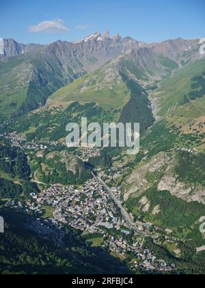 VISTA AEREA. La città di Valloire con le tre aiguilles d'arves in lontananza. Savoia, Auvergne-Rhône-Alpes, Francia. Foto Stock