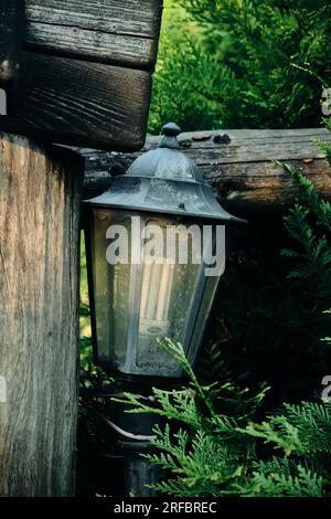 Una vecchia lampada a cherosene appesa a una trave di legno o a una finestra su un gancio d'epoca arrugginito Foto Stock