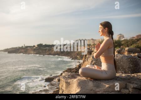 Calma felice millenaria signora caucasica con gli occhi chiusi in abbigliamento sportivo pratica yoga in posizione di loto, medita Foto Stock