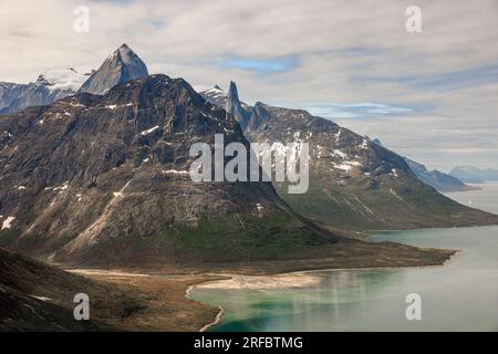 foto aerea di magnifiche montagne rocciose con lati ripidi che scendono giù nell'acqua verde blu del fiordo di tasermiut in groenlandia Foto Stock