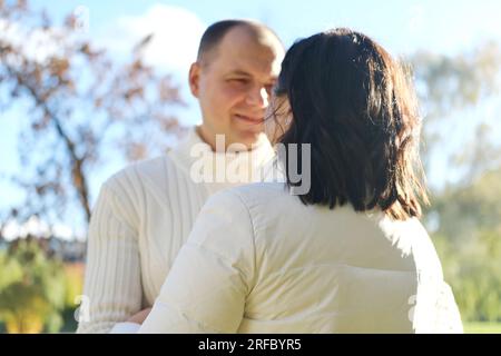 Marito e moglie fanno una passeggiata nel parco autunnale. Marito guarda con amore sua moglie. Foto orizzontale Foto Stock