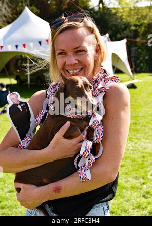 Giovane donna con il suo cane durante le celebrazioni per l'incoronazione di re Carlo, Alton, Hampshire, Regno Unito. Foto Stock