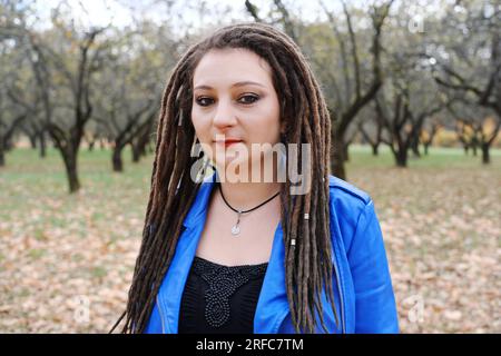 Ritratto di una donna di mezza età con una giacca di pelle blu e dreadlocks. donna che guarda la telecamera. Foto orizzontale Foto Stock