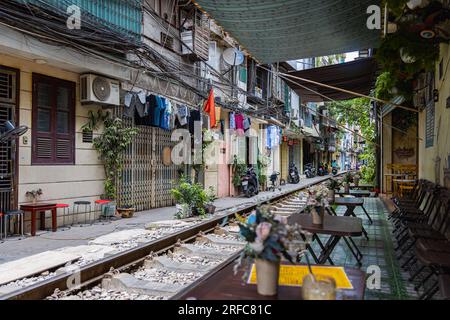 Hanoi, Vietnam - 28 maggio 2023: Train Street ad Hanoi è una stradina stretta e trafficata con binari. Case a maglia vicine, adornate di piante, distano pochi centimetri da qui Foto Stock