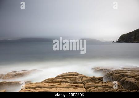 Costa rocciosa a Elgol, affacciata sul Loch Scavaig fino al Black Cuillin avvolto dalla nebbia Foto Stock