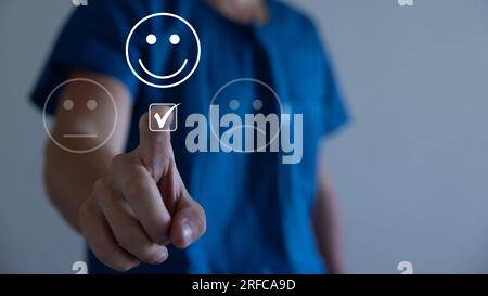 Concetto di servizio clienti e soddisfazione, uomo d'affari che preme emoticon sorridente sul touch screen virtuale. Sulla faccia felice di Smiley. Foto Stock