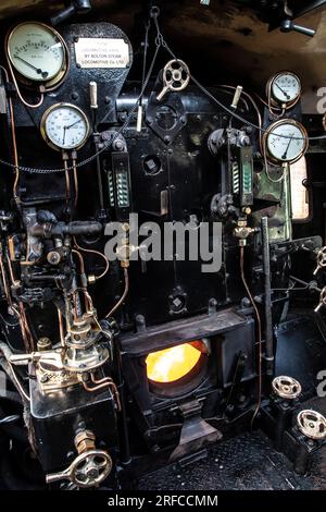 Una vista a pioli dei comandi, degli indicatori, dei livelli dell'acqua, del registratore di velocità e del firebox su una locomotiva a vapore standard 5MT British Railways Foto Stock