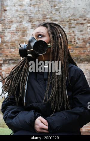 Donna che indossa una maschera antigas in piedi in un edificio in rovina. Foto verticale Foto Stock