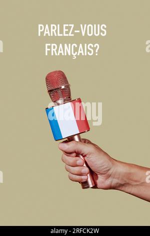 primo piano di un uomo con un microfono modellato con la bandiera della francia e la domanda "parli francese scritto in francese su un dorso marrone chiaro? Foto Stock