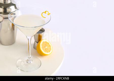 Bicchiere di gustoso martini, jigger, shaker e limone su sfondo bianco Foto Stock