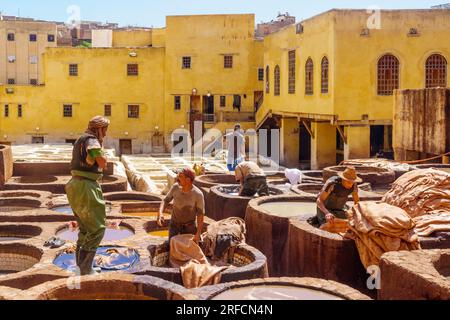 Fes, Marocco - 31 marzo 2023: Scena della conceria del cuoio, con operai e tini di pietra riempiti di vari colori. Fes, Marocco Foto Stock