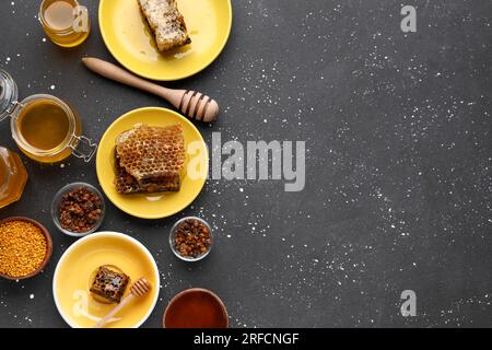 Miele dolce, pettini e polline d'api su sfondo nero Foto Stock