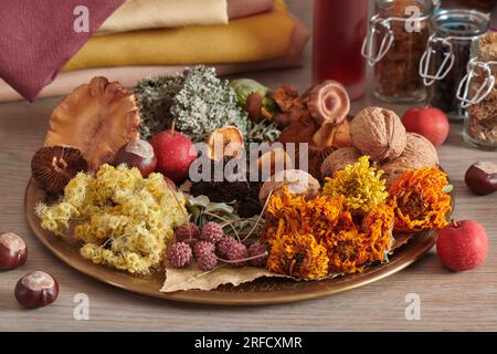 Materiale vegetale per la tintura organica di tessuti su un piatto sul mucchio di fondo di tessuti tinti a mano e vasi di erba secca Foto Stock