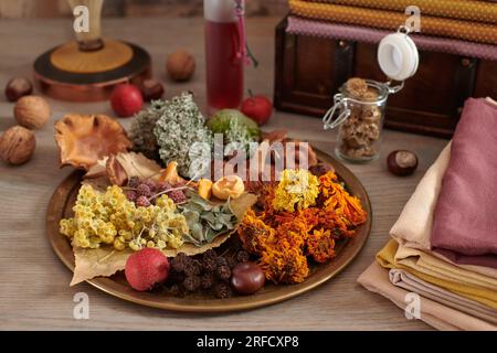 Materiale vegetale per la tintura organica di tessuti su un piatto, pila di tessuti tinti a mano sullo sfondo petto di legno con tessuti Foto Stock