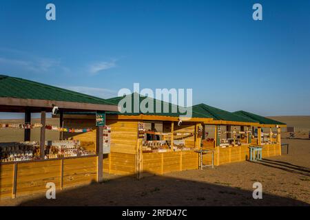 Venditori locali che vendono souvenir all'ingresso delle scogliere fiammeggianti nel deserto del Gobi vicino a Bulgan, nella Mongolia meridionale, dove si trovano importanti dinosauri Foto Stock