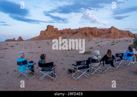 I turisti che guardano il tramonto sulle rocce arancioni del Bayan Zag, comunemente noto come le scogliere fiammeggianti nel deserto del Gobi, in Mongolia, dove importanti dinos Foto Stock