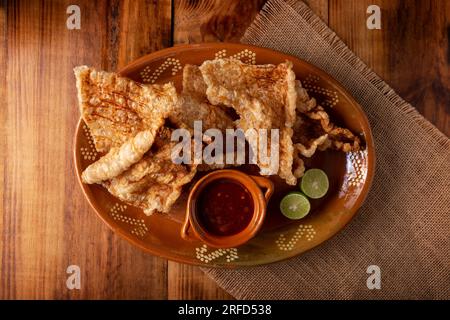 Chicharron. Crosta di maiale fritta croccante, sono pezzi di pelle di maiale fritta e ventilata, ingrediente tradizionale messicano o snack servito con succo di lime e ho rosso Foto Stock