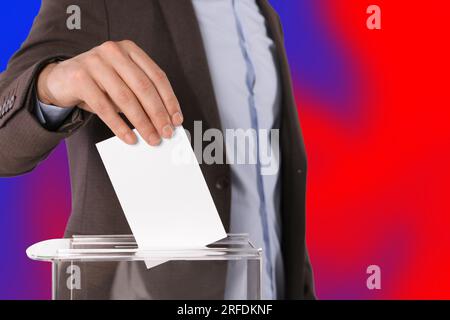 Uomo che mette il suo voto nelle urne su sfondo a colori, primo piano Foto Stock