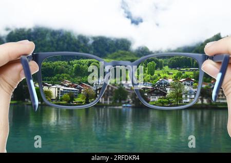 Correzione della visione. Donna che guarda attraverso gli occhiali e vede il paesaggio più chiaro Foto Stock