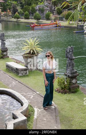 Donna turistica alla moda che esplora il Palazzo reale Balinese sull'acqua Tirta Gangga, vacanze estive sull'isola di Bali Foto Stock