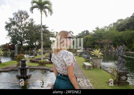 Donna turistica alla moda che esplora il Palazzo reale Balinese sull'acqua Tirta Gangga, vacanze estive sull'isola di Bali Foto Stock