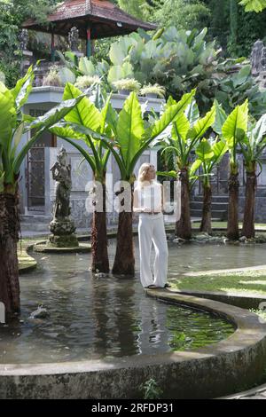 Donna turistica alla moda che esplora il Palazzo reale Balinese sull'acqua Tirta Gangga, vacanze estive sull'isola di Bali Foto Stock