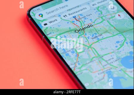 New York, Stati Uniti - 21 luglio 2023: Traffico automobilistico su Orlando google Maps sullo schermo dello smartphone vista ravvicinata con sfondo rosso Foto Stock