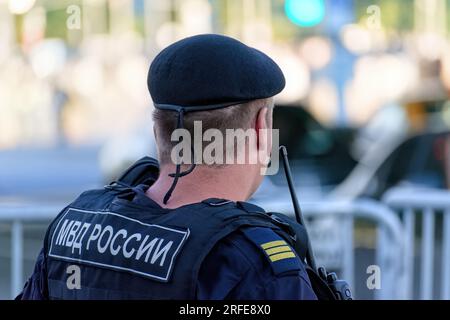 Agente di polizia russo della Guardia Nazionale in un giubbotto antiproiettile pattuglia la strada della città. Traduzione dell'iscrizione sul dorso maschile: "Ministero dell'interno Foto Stock