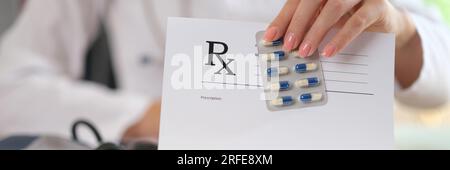 Medico seduto al tavolo con gli strumenti per la diagnostica medica e mostra prescrizione e pacchetto di farmaci. Foto Stock