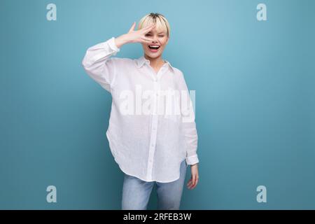 giovane donna bionda alla moda con taglio corto è vestita con una camicia bianca e jeans. stile casual Foto Stock