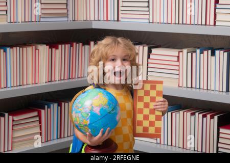 Ragazzo scolastico con globo mondiale e scacchi, infanzia. Ragazzino della scuola elementare con il libro. Piccolo studente, allievo nerd intelligente pronto a studiare. Concetto o Foto Stock