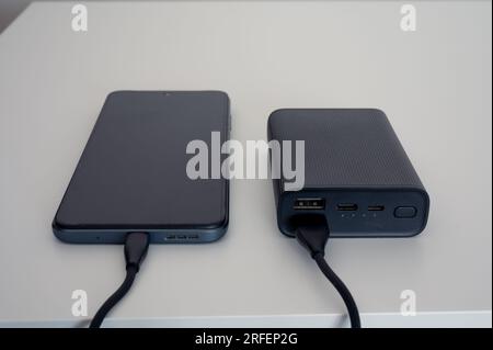 Batteria nera per ricarica mobile. Cavo nero. Su sfondo bianco Foto Stock