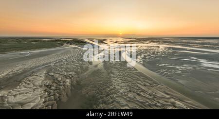 Francia, somme, Baie de somme, le Hourdel, soleil couchant sur le Hourdel à l'extrémité du cordon de galets alors que la marée basse dévoile les méandres des chenaux et les reliefs des bancs de Sable (vue aérienne) Foto Stock