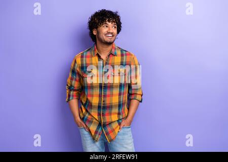 Foto del giovane ragazzo indiano medio orientale sembra spazio vuoto indossando un elegante modello di camicia casual a quadri isolato su sfondo viola Foto Stock