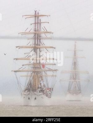 Francia, Calvados, Honfleur, Armada 2023, Grand Parade, Le Tallships Dar Mlodziezy e Statsraad Lehmkuhl navigano sotto il ponte di Normandia sotto la pioggia torrenziale Foto Stock