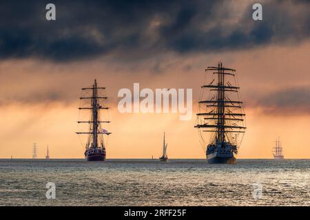 Francia, Calvados, Honfleur, Armada 2023, Grand Parade, Tallships Dar Mlodziezy, Thalassa, le Francais, Bima Suci ed Etoile Molène salpano al tramonto e nel cielo tempestoso Foto Stock