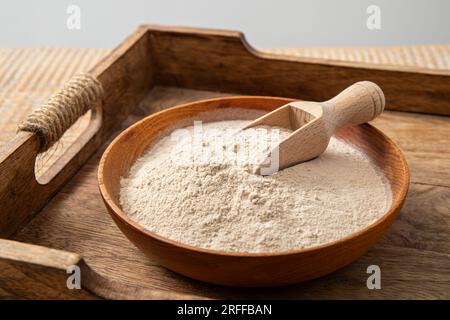Polvere di farina di buccia di psicllium su recipiente di legno e cucchiaio in casa. Benefici per la salute del concetto di farina di Psyllium. Foto Stock