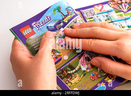 Tambov, Federazione Russa - 21 dicembre 2021 Una donna che sfoglia un catalogo Lego sulla pagina con i set Lego Friends. Foto Stock