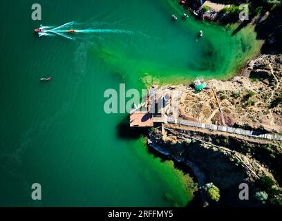 Foto aerea con droni dall'alto verso il basso di un gruppo di persone in piedi su tavole da paddle nel lago verde Kapchagay vicino al faro in Kazakistan Foto Stock