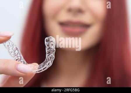 Una ragazza con un bel sorriso tiene degli allineatori in mano Foto Stock