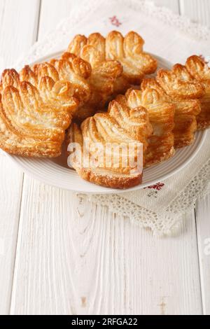 Biscotti di pasta sfoglia di palmina italiani ricoperti di zuccheri per primo piano sul piatto sul tavolo. Verticale Foto Stock