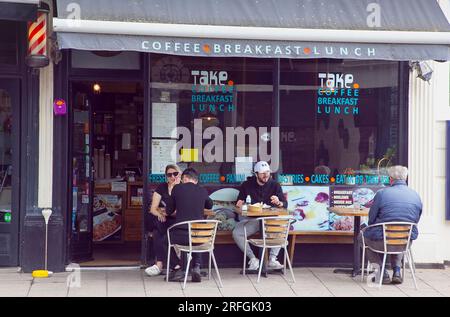 Inghilterra, East Sussex, Brighton, Hove, Western Road, La gente Sat fuori porta porta il Turkish Cafe per mangiare e bere. Foto Stock