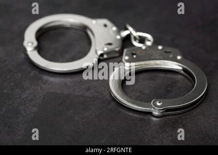 Le manette in metallo su sfondo nero. Manichetta o arco. Manette della polizia Foto Stock