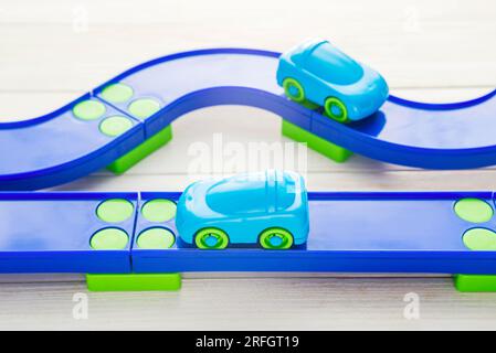 Macchinine giocattolo e pista da corsa su sfondo di legno bianco Foto Stock