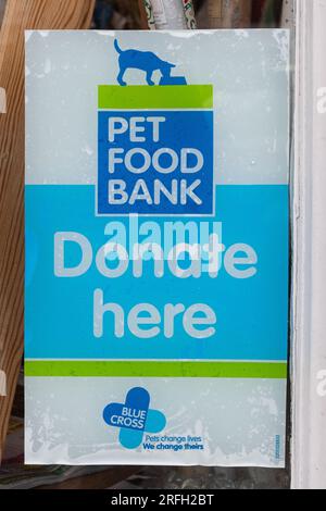 Avviso poster per una PET Food Bank in una vetrina di un negozio di beneficenza Blue Cross Animal Welfare per chiedere donazioni, Inghilterra, Regno Unito Foto Stock