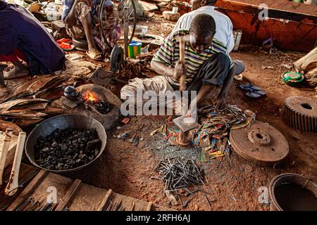 Artigianato africano chiodi da rottami metallici con un martello . Costruzione di barche in legno Pinasse sulla riva del fiume a Mopti , Mali , Africa occidentale . Foto Stock