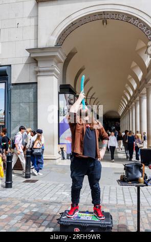 Il mago di strada australiano Jason Maher ingoia una mongolfiera mentre si esibisce e intrattiene una folla a Covent Garden nel West End di Londra, WC2 Foto Stock