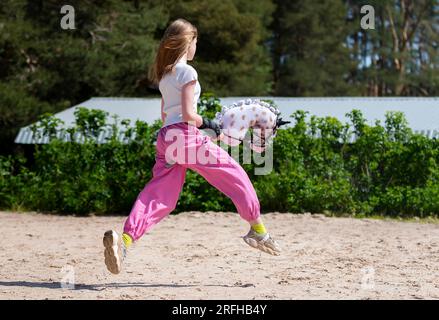 Ragazza che salta su un cavallo da hobby. Campione. Sport a cavallo. Luce estiva. Sfondo verde di alberi all'aperto. Il percorso Cavaletti. Sport infantile. Banner Foto Stock