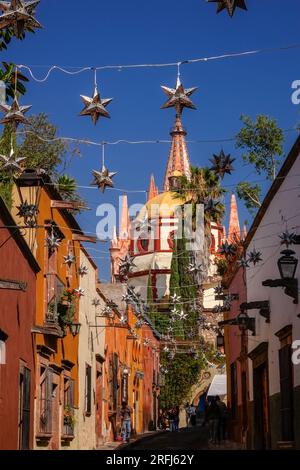 Stelle messicane di latta si stagliavano lungo la Calle Aldama acciottolata con il campanile rosa della Parroquia de San Miguel Arcangel che svetta sopra nel centro storico della città di San Miguel de Allende, Messico. Foto Stock